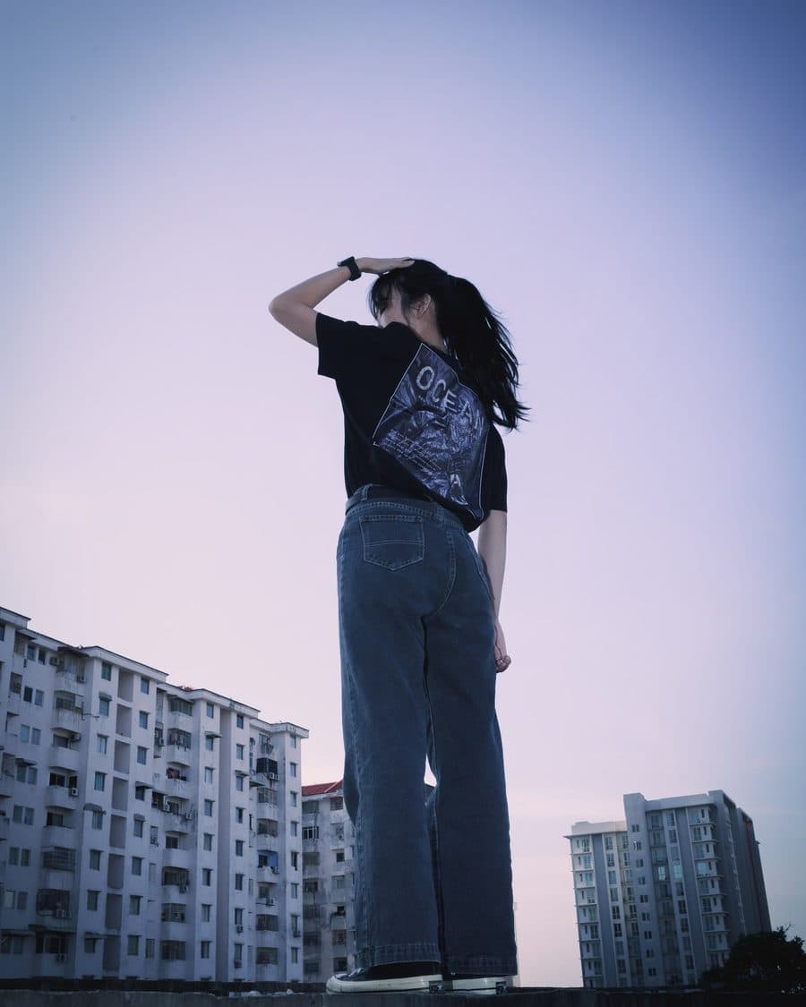 A portrait shot on a rooftop at dusk against Kuala Lumpur apartment blocks