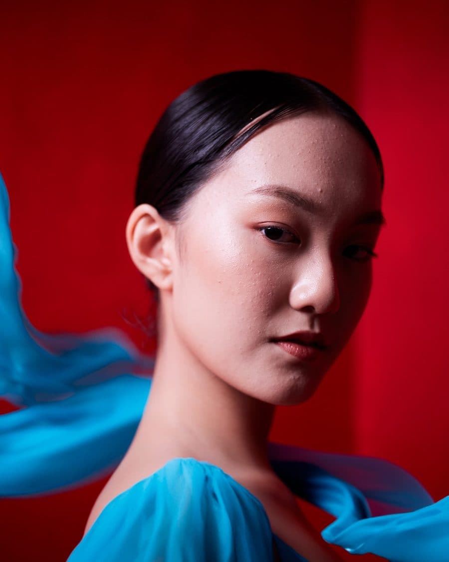A beauty portrait lit in red and blue, shot in studio