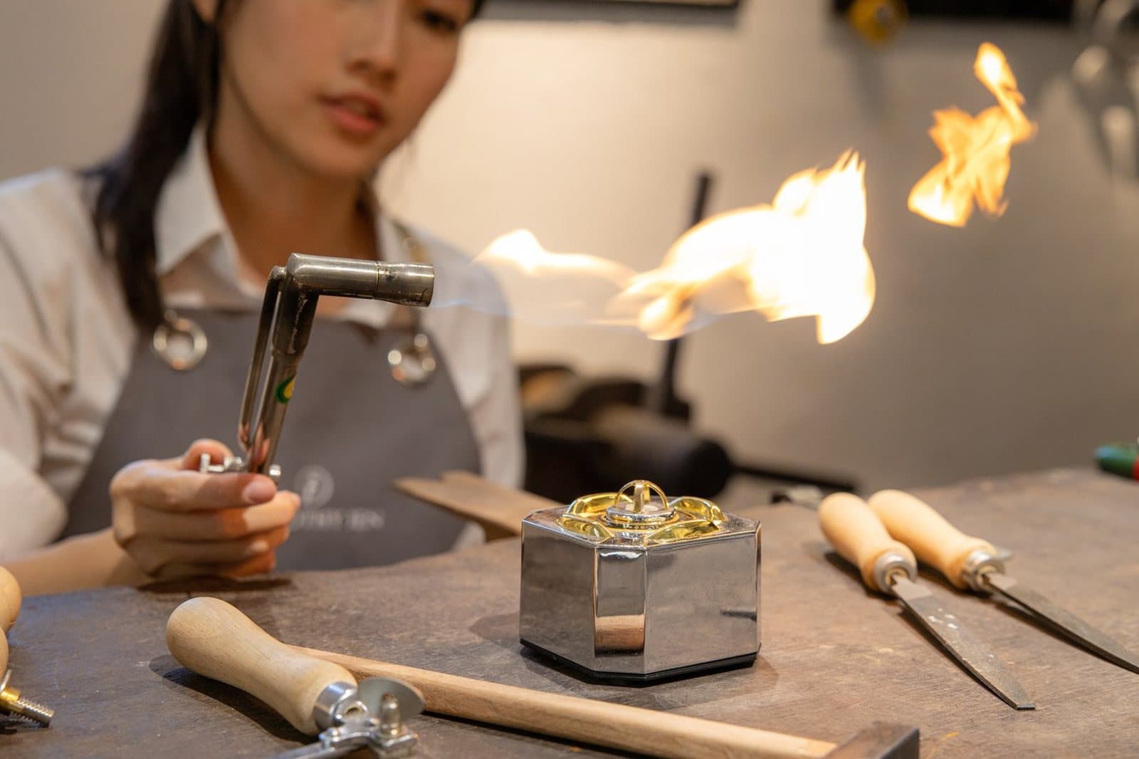 A jeweller working with a torch at their bench in a Malaysian workshop