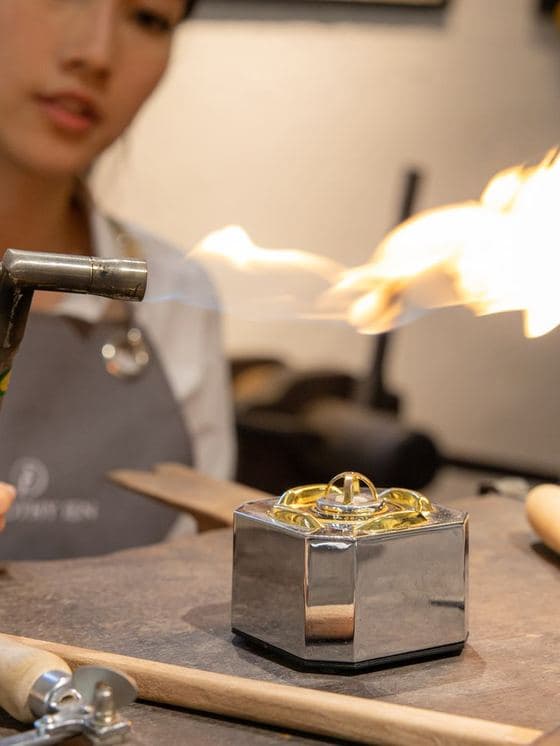 A jeweller's torch flaring over a ring on the bench, shot close
